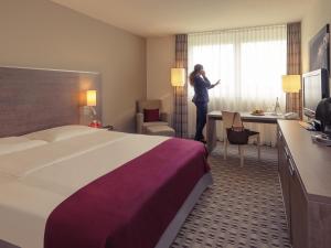 a woman standing in a hotel room with a bed at Mercure Hotel Frankfurt Eschborn Ost in Eschborn