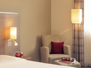 a hotel room with a chair and a bed at Mercure Hotel Frankfurt Eschborn Ost in Eschborn