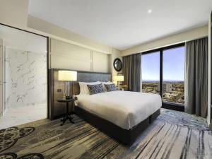 a bedroom with a large bed and a large window at Sofitel Adelaide in Adelaide