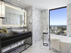 a bathroom with a tub and a sink and a mirror at Sofitel Adelaide in Adelaide