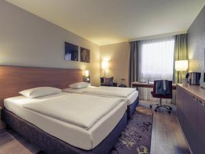Una habitación de hotel con dos camas y un escritorio. en Fürther Hotel Mercure Nürnberg West, en Fürth