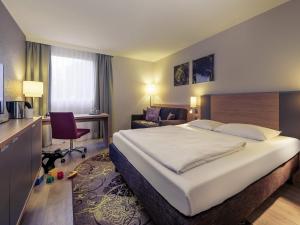 a hotel room with a large bed and a chair at Fürther Hotel Mercure Nürnberg West in Fürth