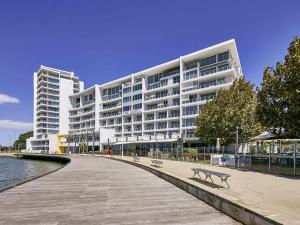 a large white building with a bench in front of it at The Sebel Mandurah in Mandurah