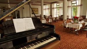a piano in a room with a table and chairs at River Side Hotel in Mingachevir