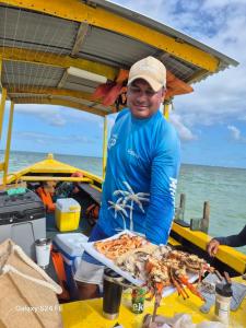 un hombre de pie junto a una mesa con una bandeja de comida en Villa da Apa, en Japaratinga 84 fotos más