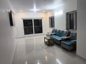 Una sala de estar con un sofá azul y un televisor. en Iris Groove Ooty by Avkanz, en Ooty