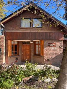 una casa de ladrillo con puerta y ventanas marrones en CosmoSur - El Bolson Centro, en El Bolsón