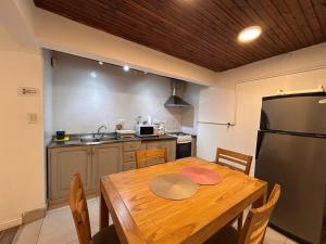 Una cocina con una mesa de madera y un refrigerador. en CosmoSur - El Bolson Centro, en El Bolsón 6 fotos más