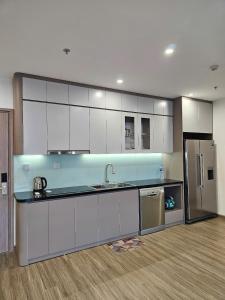 a kitchen with white cabinets and a stainless steel refrigerator at Luxhomes TC1 Canopy Smart City in Phú Thú