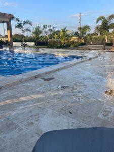 a swimming pool with blue water and palm trees at Jeda Village in Higuey
