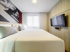 a bedroom with a large white bed and a flat screen tv at Mercure Sao Paulo Moema Times Square in Sao Paulo +221 photos