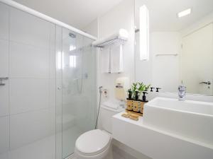 a white bathroom with a toilet and a sink at Mercure Sao Paulo Moema Times Square in Sao Paulo