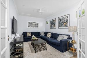 a living room with a blue couch and a tv at Lambent - Casuarina House in Casuarina