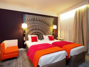 ein Hotelzimmer mit einem großen Bett und einem Stuhl in der Unterkunft Mercure Nantes Centre Grand Hotel in Nantes