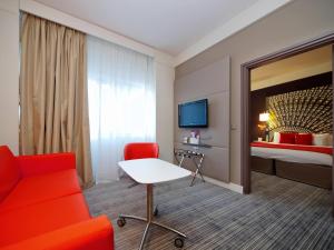 ein Hotelzimmer mit einem roten Sofa und einem Bett in der Unterkunft Mercure Nantes Centre Grand Hotel in Nantes