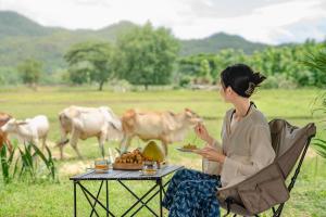 パーイにあるPuripai Villa Wellness & Retreatの食べ物が置かれたテーブルと椅子に座っている女性