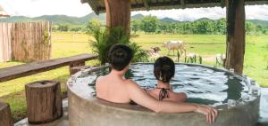 パーイにあるPuripai Villa Wellness & Retreatの野原のホットタブに座って2名