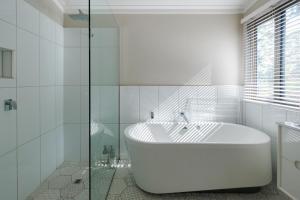 La salle de bains blanche est pourvue d'une baignoire et d'une douche en verre. dans l'établissement The Floating Forest, à Denmark 179 autres photos