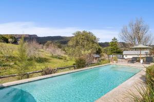 a large swimming pool in a yard with a garden at Hide and Seek Estate, Kangaroo Valley in Upper Kangaroo River