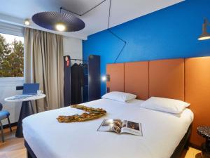 a hotel room with a bed with a book on it at Ibis Sallanches Porte du MontBlanc in Sallanches +50 photos