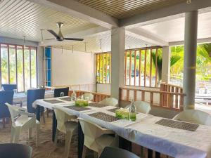 a dining room with tables and chairs and windows at White Sand in Himandhoo  +49 photos