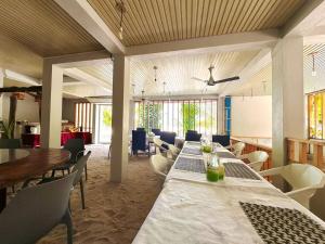 a dining room with tables and chairs and windows at White Sand in Himandhoo 