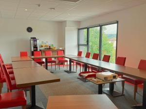 an empty room with tables and red chairs at ibis Dijon Sud in Perrigny-lès-Dijon