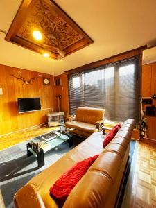 Una sala de estar con un sofá de cuero y un televisor. en アラン別邸自然溢れる呼人の一軒家, en Yobito 56 fotos más