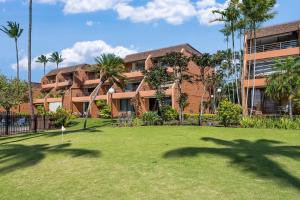 a building with palm trees in front of a yard at Kuleana 321 · KU 321 Spectacular Ocean Views in Kahana
