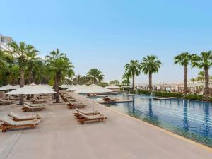 a pool at a resort with lounge chairs and umbrellas at Fairmont Bab Al Bahr in Abu Dhabi