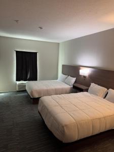 a hotel room with two beds and a window at Hotel de Luxe Extended Stay in Sulphur