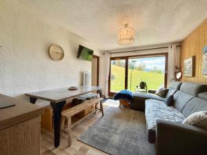 un soggiorno con un divano e un tavolo di Appartement cosy avec terrasse et parking proche centre - FR-1-505-235 a Notre-Dame-de-Bellecombe