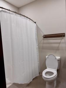 a bathroom with a toilet and a shower curtain at Hotel de Luxe Extended Stay in Sulphur