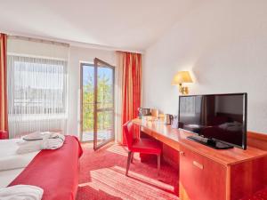 a hotel room with a desk with a television and a bed at Mercure Hotel Bad Duerkheim An Den Salinen in Bad Dürkheim