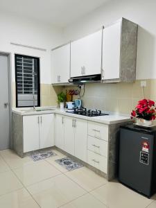 a kitchen with white cabinets and a black refrigerator at FA Homestay KLIA 3rd Unit in Nilai