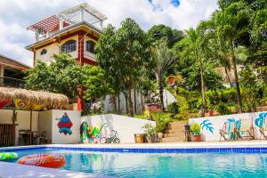 a swimming pool in front of a house at Screaming Gecko Hostel in Busuanga