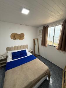 a bedroom with a bed with blue pillows and a window at Apartamentos São Pedro da Aldeia in São Pedro da Aldeia