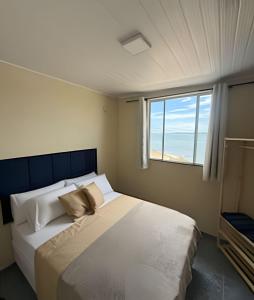 a bedroom with a large white bed with a window at Apartamentos São Pedro da Aldeia in São Pedro da Aldeia
