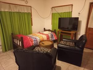 a living room with two chairs and a bed and a television at La Casa de Doña Adela in Eugenio Bustos