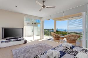 a living room with a television and a balcony at Dee's Retreat Rainbow Beach in Rainbow Beach