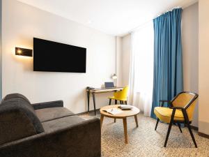 a living room with a couch and a tv at Mercure Epinal Centre in Épinal