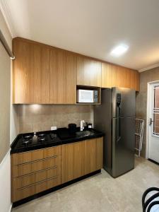 eine Küche mit Holzschränken und einem Edelstahlkühlschrank in der Unterkunft Apto 3 PRÓX. Shopping | Hospital Regional, Premium in Três Lagoas