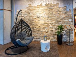 a swing chair sitting in front of a brick wall at Mercure Salzburg City in Salzburg