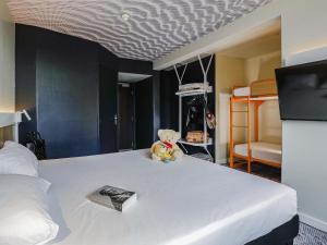 a teddy bear sitting on top of a bed at Ibis Luxembourg Airport in Luxembourg