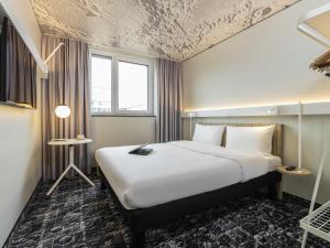 a bedroom with a large white bed in a room at Ibis Luxembourg Airport in Luxembourg