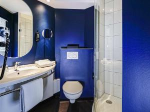 a blue bathroom with a toilet and a sink at Ibis Luxembourg Airport in Luxembourg +106 photos