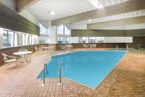 ein großer Pool in einem Gebäude mit Tischen und Stühlen in der Unterkunft Super 8 by Wyndham Wisconsin Dells in Wisconsin Dells