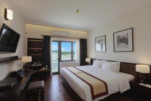 une chambre avec un grand lit et une grande fenêtre dans l'établissement Huong Giang Hotel Resort & Spa, à Hue