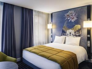 a hotel room with a bed with a painting on the wall at Mercure Nancy Centre Place Stanislas in Nancy