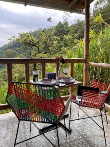 a table and chairs on a porch with a view at RIYA Tesoro de la Montaña Cabaña Haly in Ibagué